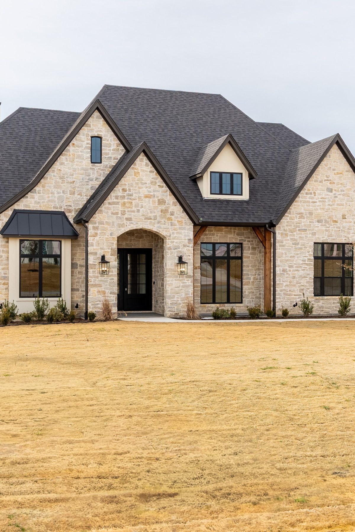 The front elevation of a house built by JSF Homes — stone, with steep gables, a dormer and an arched entry.